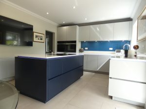 modern kitchen with navy blue island, light grey kitchen units with matching cabinets and a blue backsplash